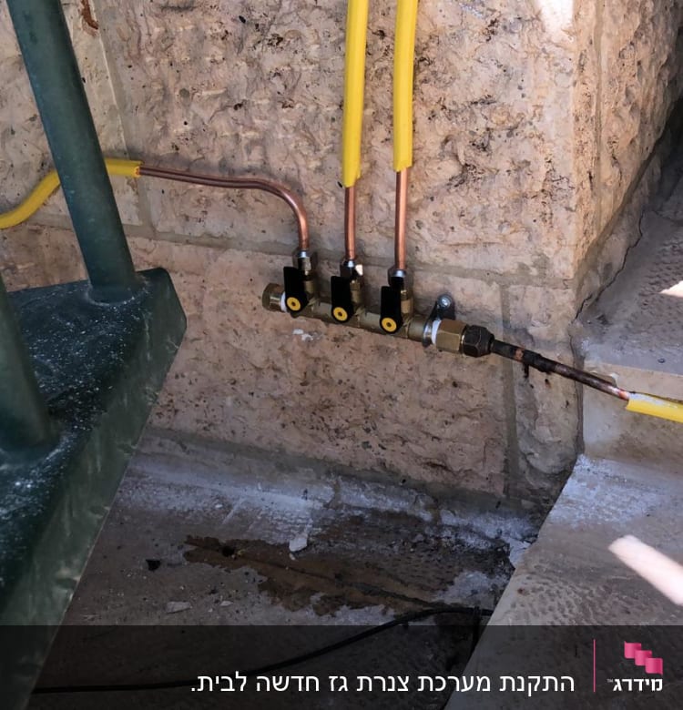 צינורות גז צהובים מחוברים לשסתומים על קיר אבן